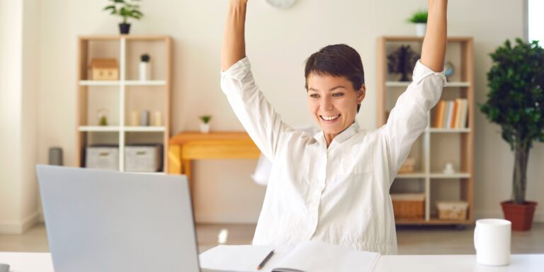 Person cheering in front of a computer screen