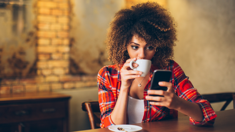 Person in cafe on their phone and drinking coffee