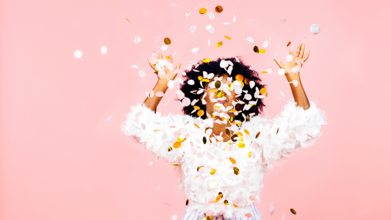 Person celebrating with confetti in front of pink background