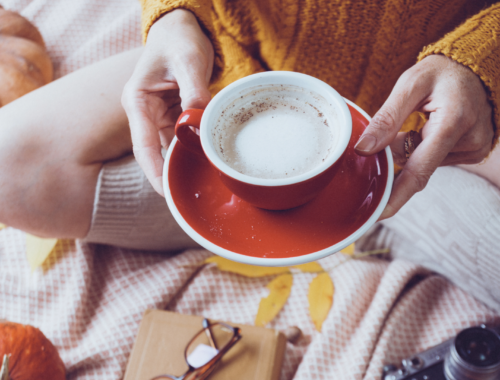 Girl holding coffee mug on bed